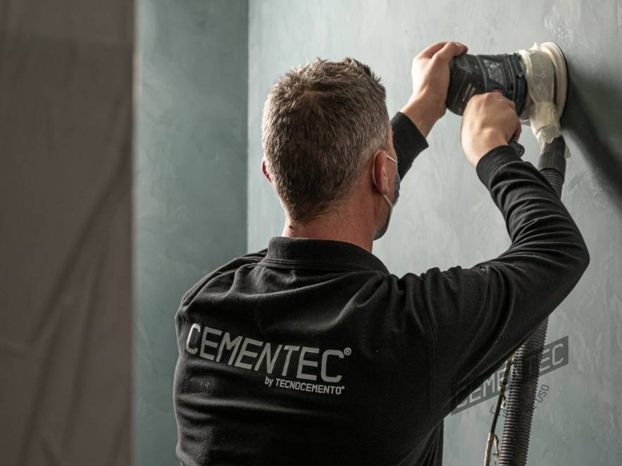 One of Cementec's ready-to-use microcement applicators sanding a wall.